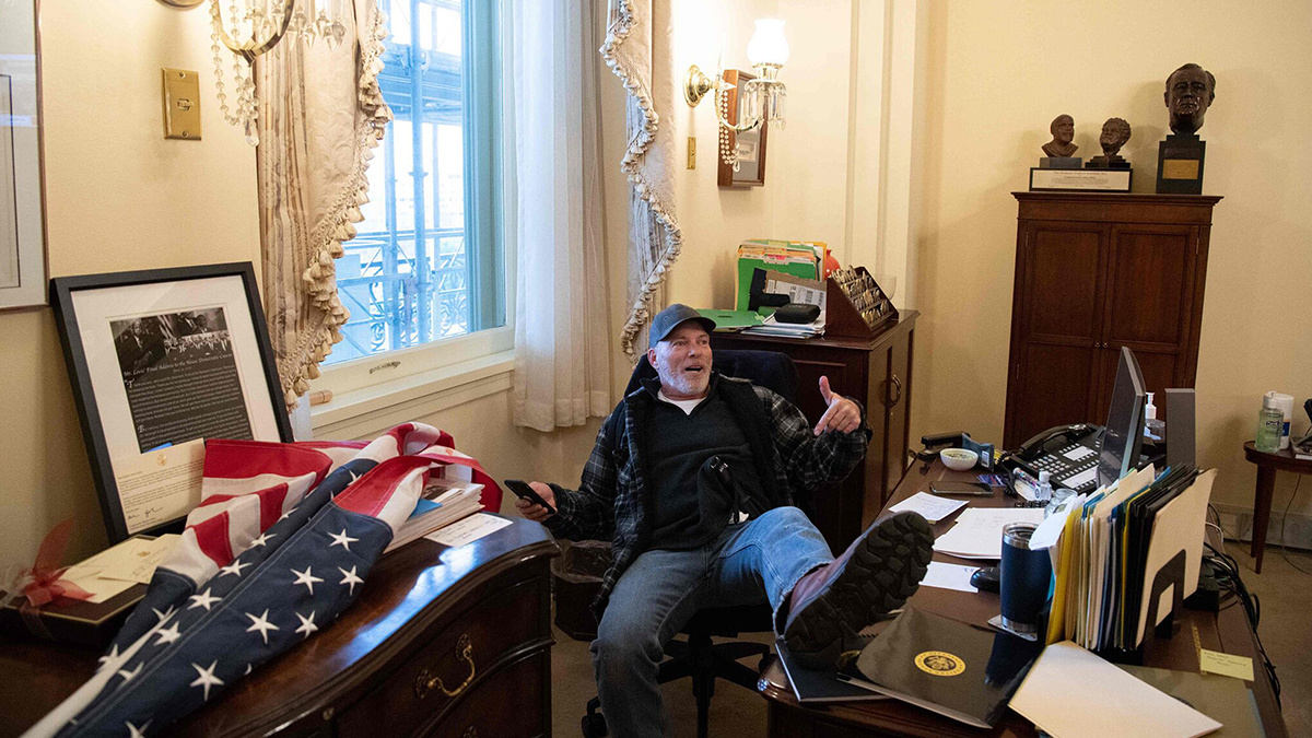 A Trump supporter sits at Speaker Nancy Pelosi's desk after rioters stormed the Capitol Building